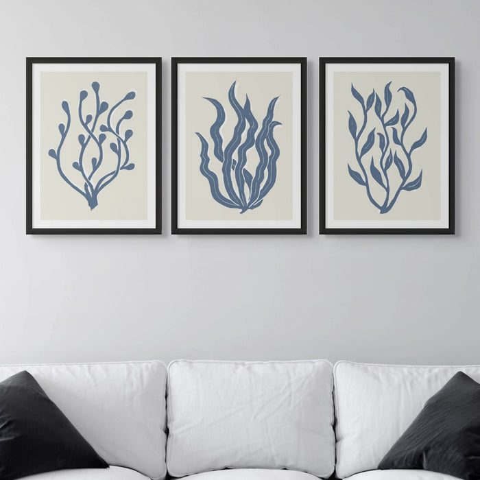 A set of three framed indigo blue lino cut seaweed art prints in modern living room frame.