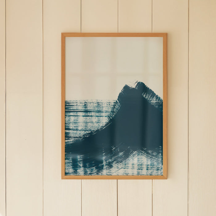 A framed abstract art print featuring swirls of dark blue and black on a light background, resembling ocean waves. The art print is shown on a cream wooden pannelled wall.