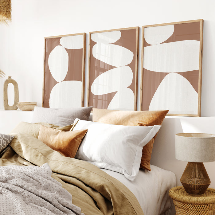 Set of three framed abstract art print above bed. Set of three mocha brown abstract balancing stones prints.
