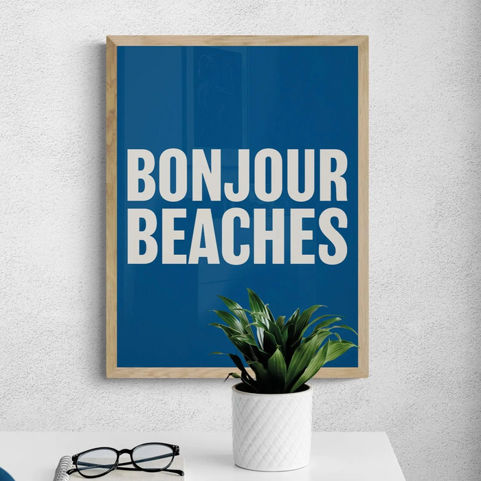 A colourful typography art print with the text 'BONJOUR BEACHES' in bold white letters on a navy blue background, framed on wall.