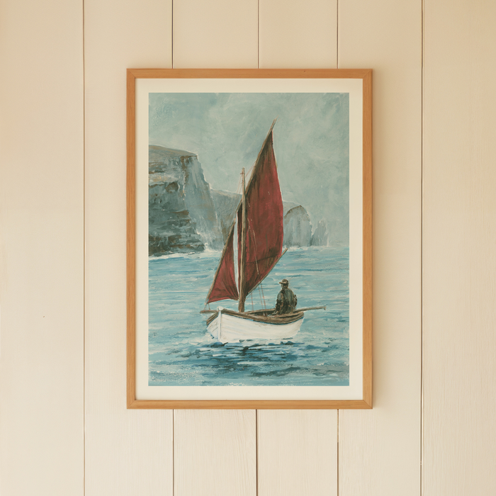 Framed artwork of a sailboat with a red sail on a beige wall.