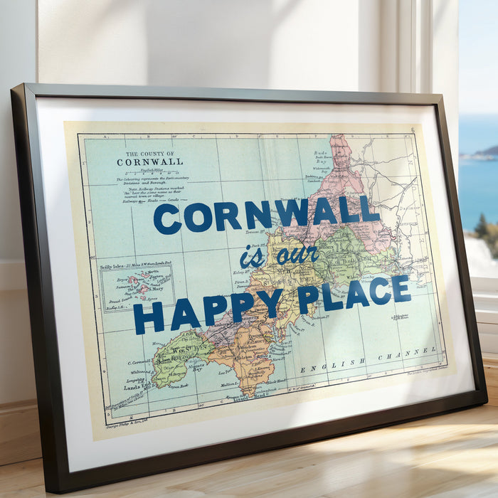 Framed map of Cornwall with 'Cornwall is our happy place' text, placed indoors with a window view.