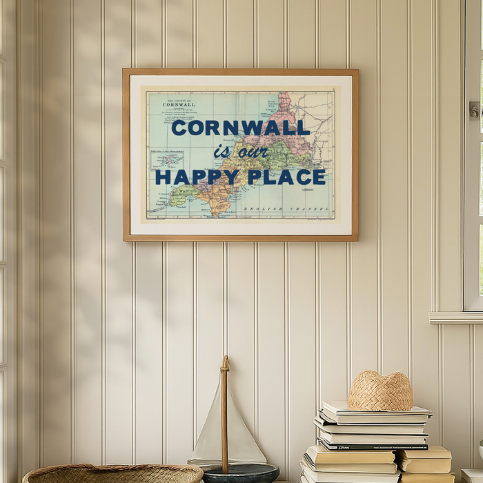Framed map of Cornwall with 'Cornwall is our happy place' text on a wall with decorative items below.