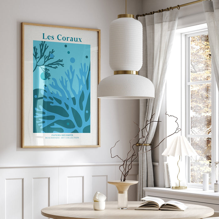 Framed coral art print in dining room with round table, chairs, and a window with curtains.