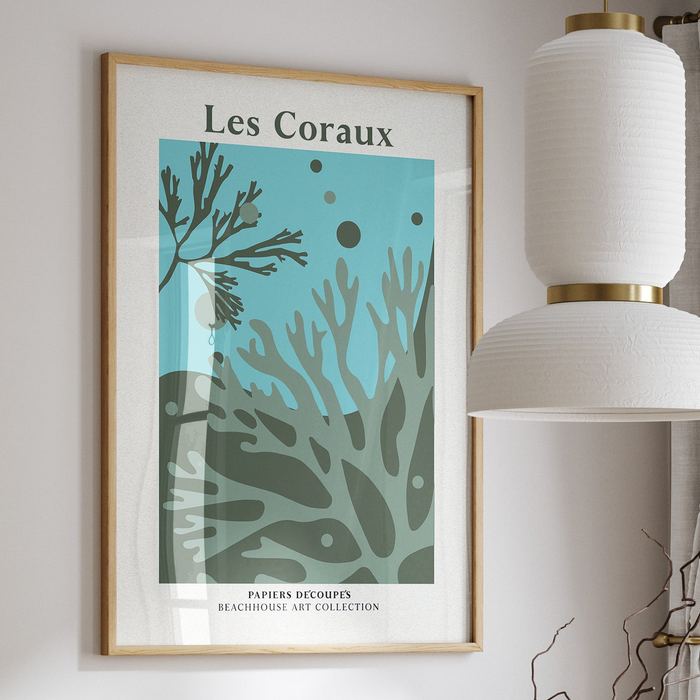A framed coral art print in green, framed with a natural wood frame.
