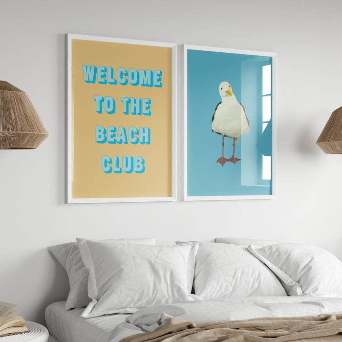 Two framed artworks on a wall above a bed, one with 'Welcome to the Beach Club' text and the other with a bird illustration.