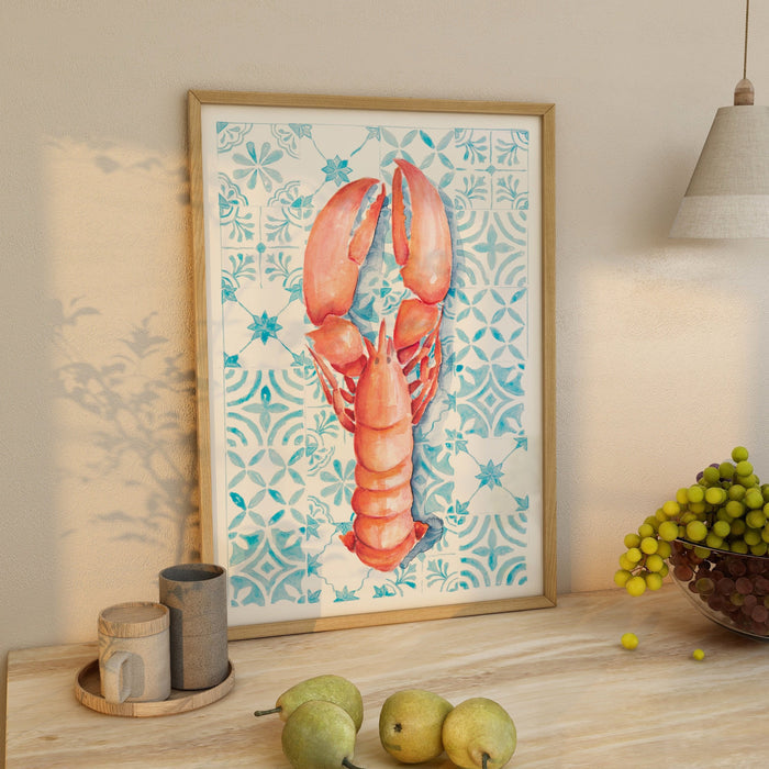Framed lobster print on blue Mediterranean tile background, hand-painted kitchen wall art displayed on a wooden countertop.