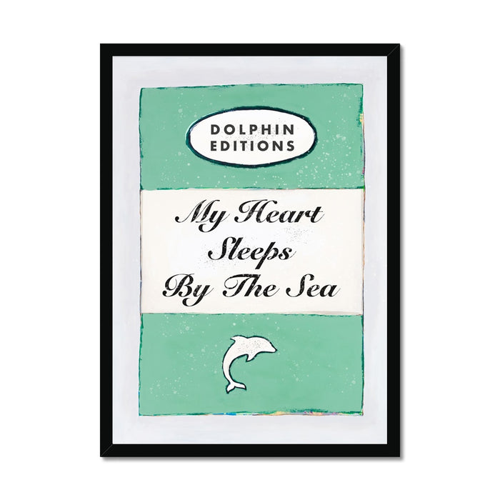 Framed art print of a vintage book cover with the title 'My Heart Sleeps By The Sea' and a small illustration of a fish at the bottom.