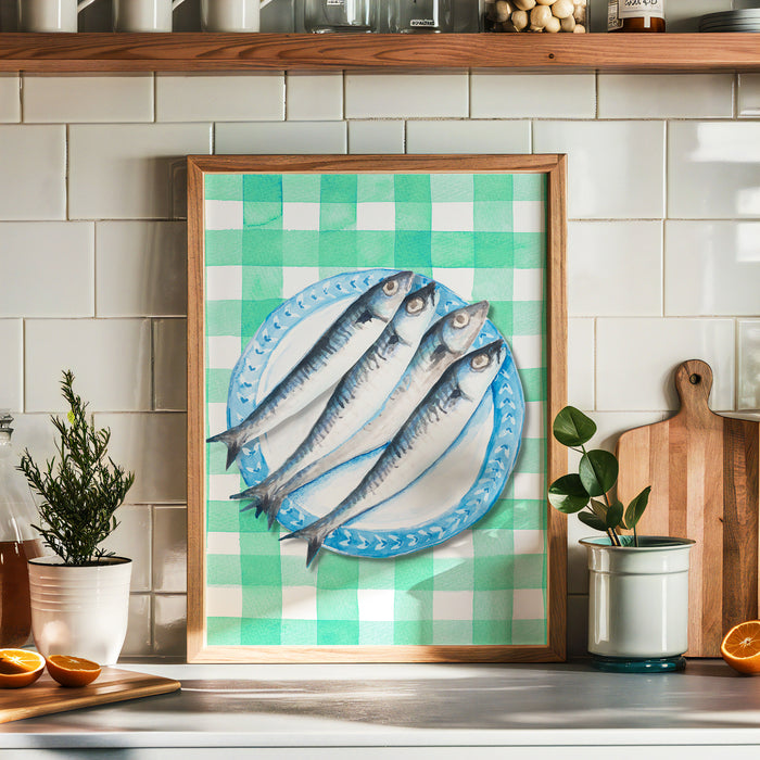 Framed artwork of fish on a plate. Sardines on a blue plate, placed on a green gingham tablecloth presented in kitchen.