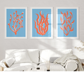 Three framed artworks of red coral on a blue background above a white sofa.
