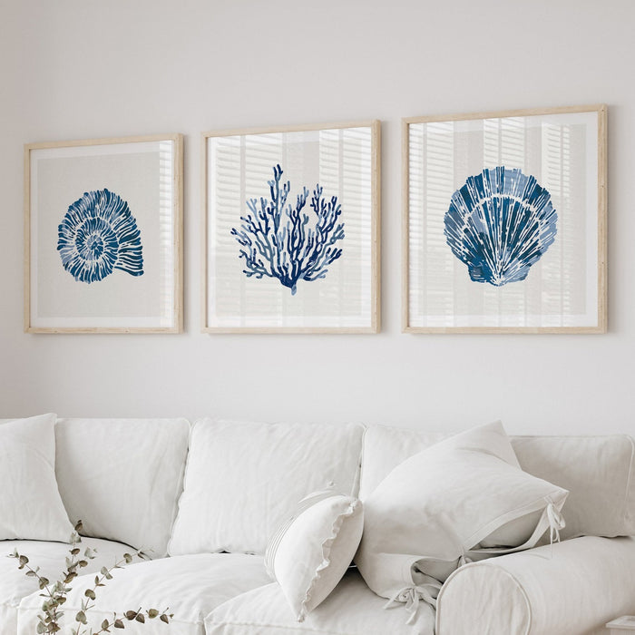 Set of three indigo coral and shell art prints framed above a sofa, coastal wall art in blue tones