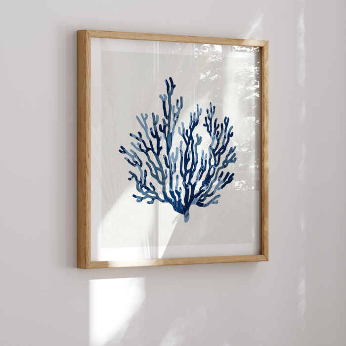 Blue coral art print framed with a natural wood framed on white wall.