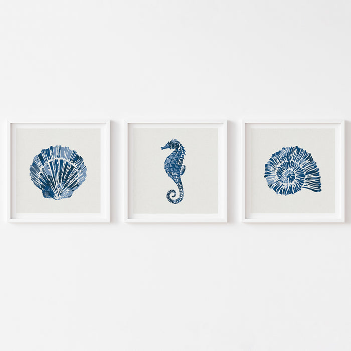 Set of three indigo shell and seahorse prints, coastal wall art displayed as a matching trio on a white background.