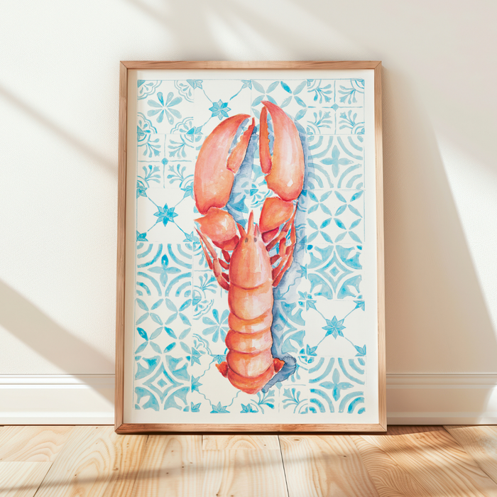 Framed artwork of a lobster on a patterned background in a room with wooden floor and white walls.