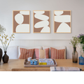 set of three white and brown abstract art prints on wall in dining room.