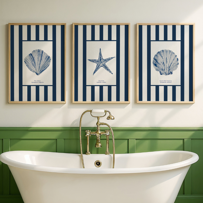 Set of three shell art prints in bathroom with a white bathtub, gold tap, and three framed coastal-themed prints on the wall.