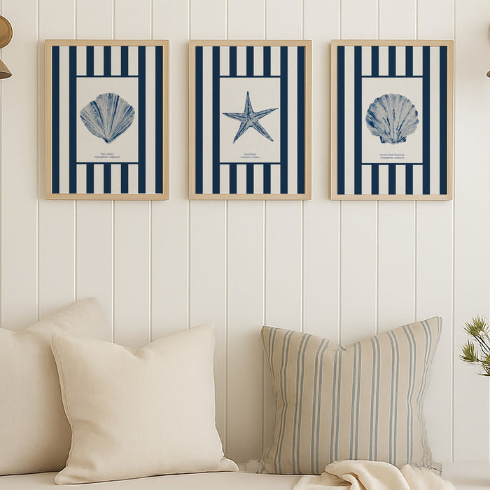 Three framed coastal-themed prints above a sofa with decorative pillows and a blanket.