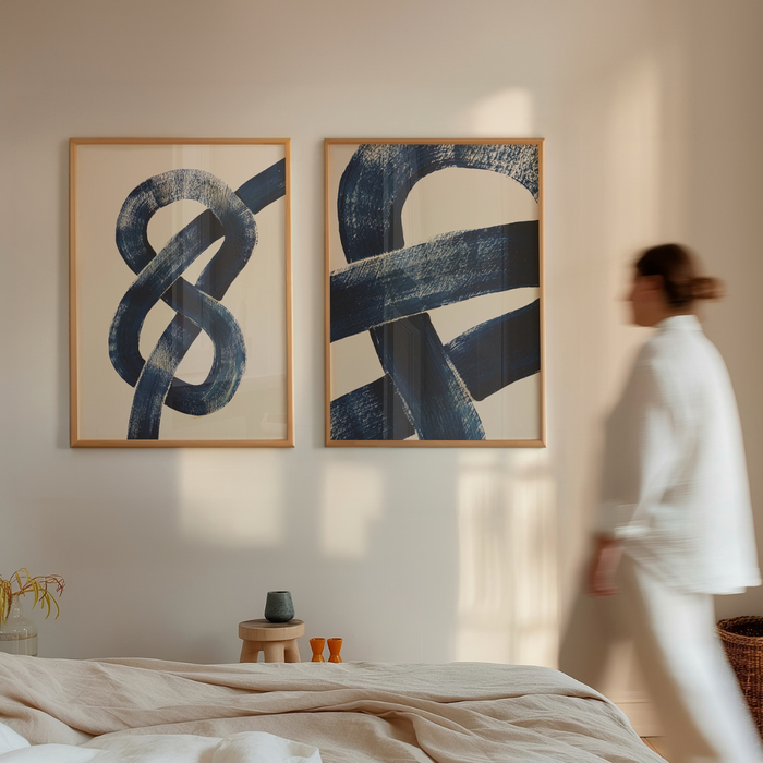 Set of two blue abstract wall art prints on a wall with a person walking by.