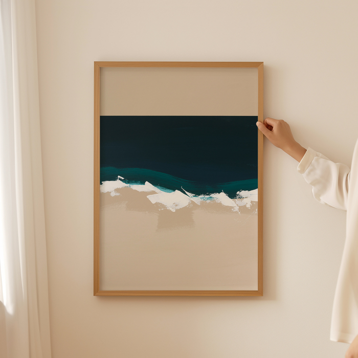 Person hanging a framed artwork of a beach scene on a wall.