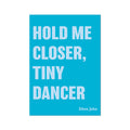 A colorful art print with the text 'HOLD ME CLOSER, TINY DANCER' in white capital letters on a bright blue background, signed by Elton John at the bottom.